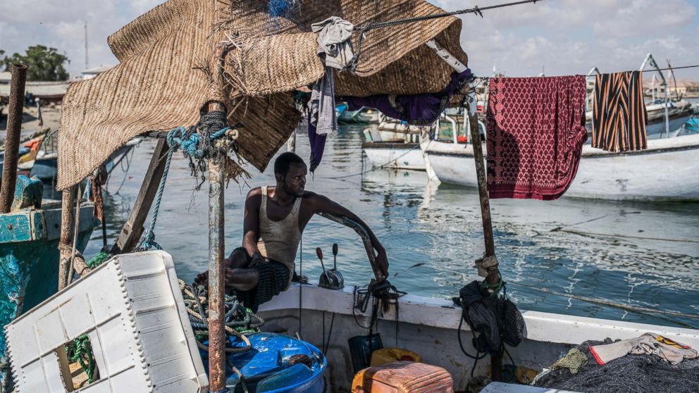 PHOTO: A fisherman relaxes in the shade of his boat, docked in the midday heat of Bosaso port in Somalia. From 2005 to 2012, piracy off Somalia posed the predominant threat to world shipping. 